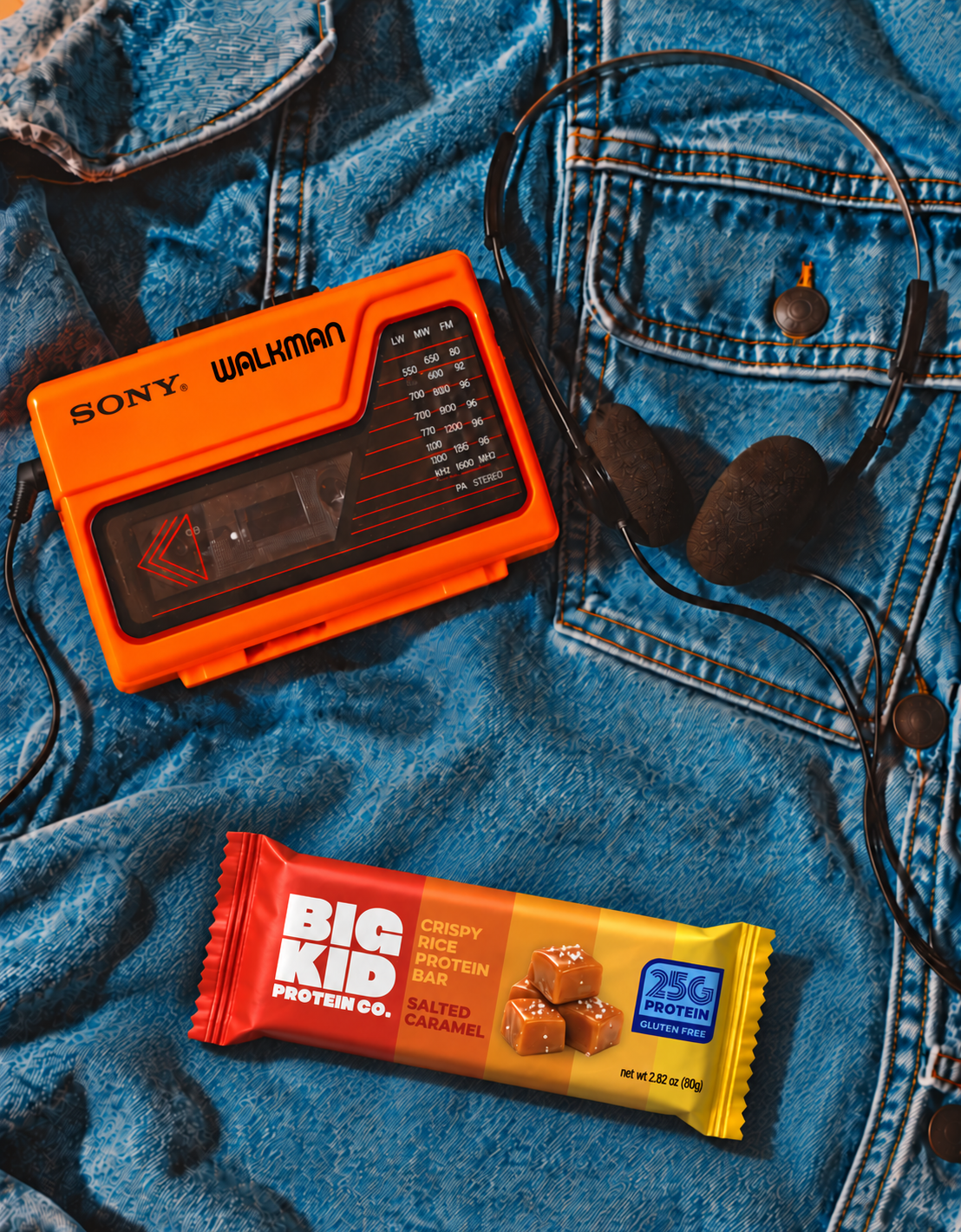 A Big Kid Salted Caramel bar beside an orange Sony Walkman and headphones on denim